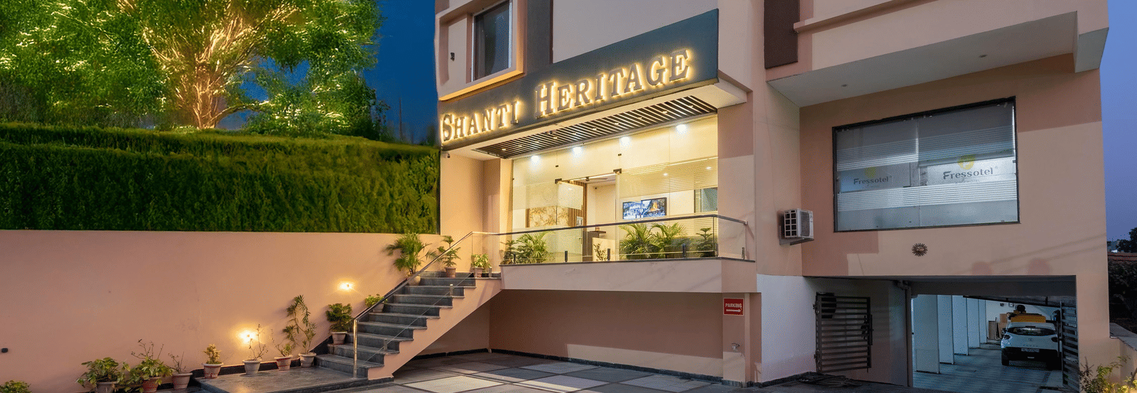 The hotel building entrance and paved driveway at late evening showing trees at Perfectstayz Premium Shanti Heritage, Haridwar