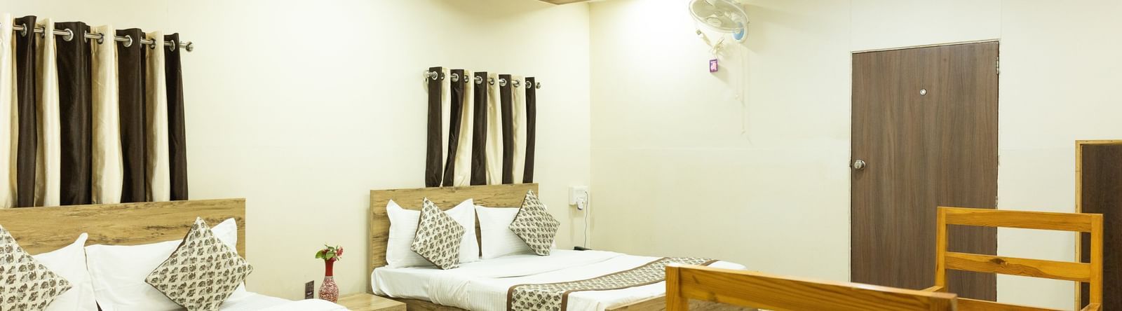 A guest room with two beds, a wooden dining set and ceiling lights at Daksh Resort & Amusement Park.