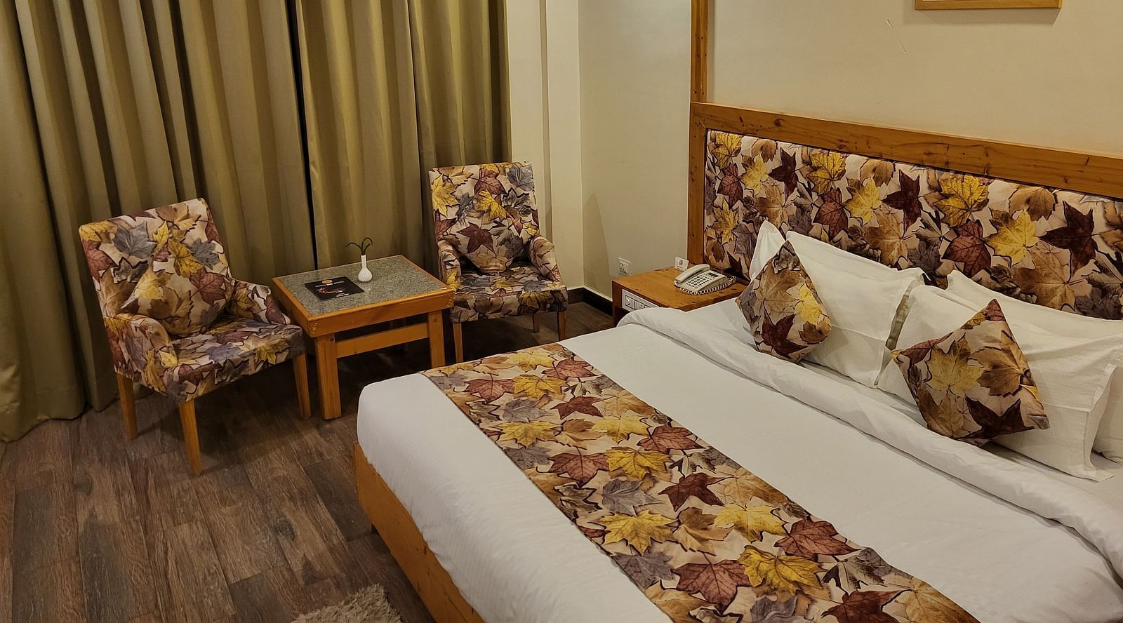 Side angle of the bedroom, featuring comfortable seating, elegant curtains, and wooden flooring at Dagshai Manor Kasauli - Inde Hotels.