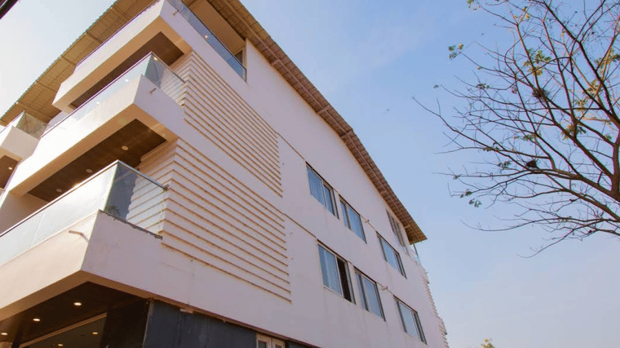 A low-angle exterior view with the modern white facade of Estherea Elite, Morjim against a blue sky at 