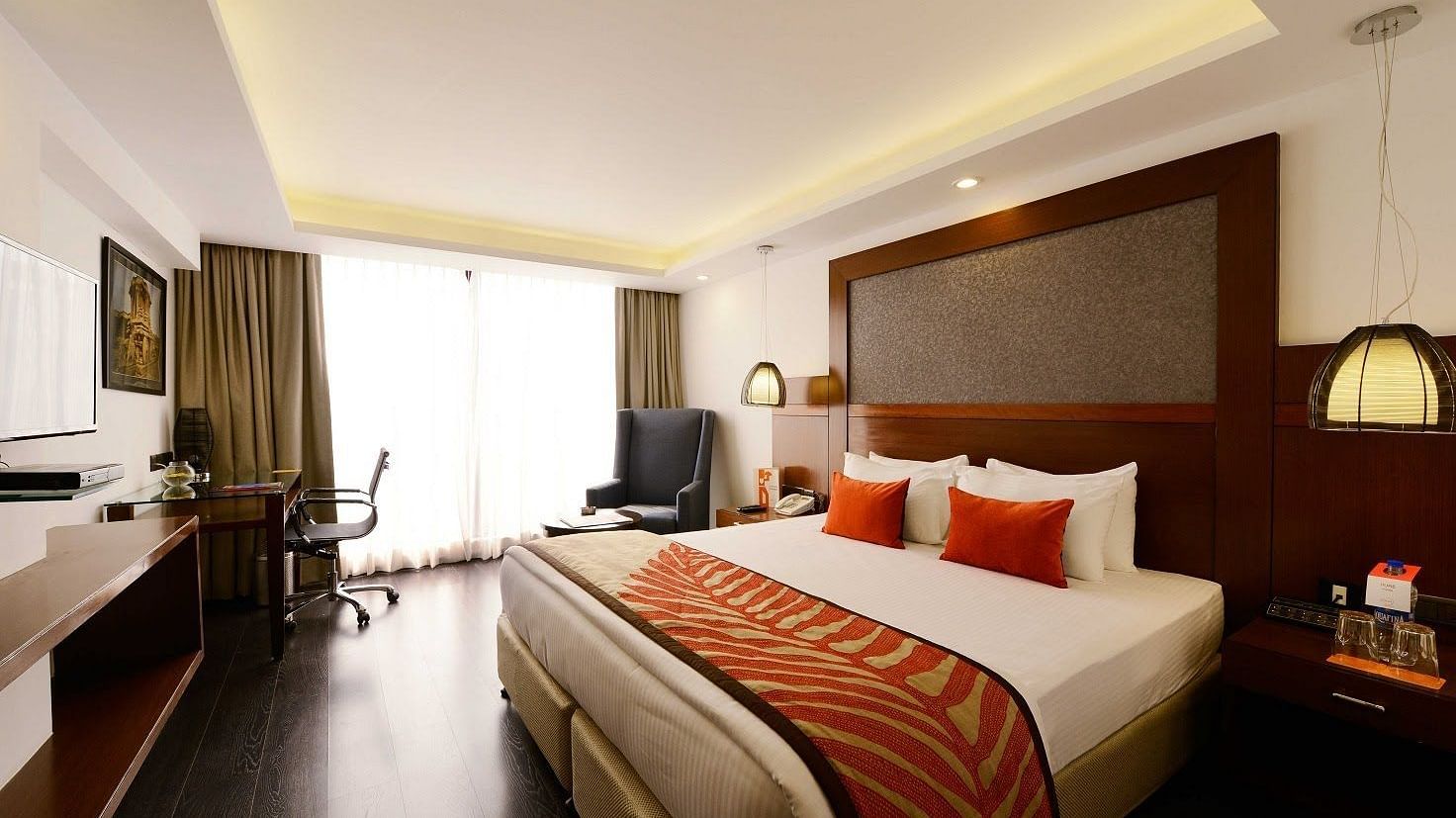Deluxe Room at The Cunningham Hotel featuring a with a king size bed, warm lighting, wooden accents, a workspace, and a seating area