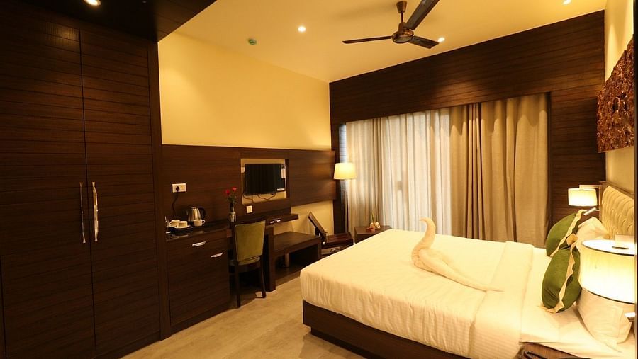 A hotel bedroom with a large bed, bedside tables, and a ceiling fan, designed with contemporary wooden and textured wall accents - Sea Hills Hotels, Sri Vijaya Puram (Port Blair)