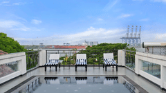 Rooftop swimming pool deck at The Old Court House by Abad, one of the luxury hotels with swimming pool in Kochi, showcasing three striped lounge chairs, glass railings, and a scenic view of the harbour under a bright sky.