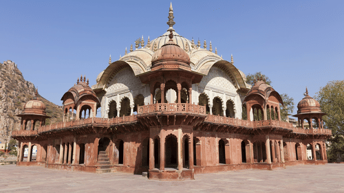 Facade view of a building with red sandstone and white marble under a clear blue sky