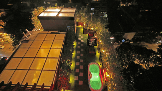 Rooftop view of Theory9 - Premium Service Apartments in Mumbai, featuring a green-lit pool on the side.
