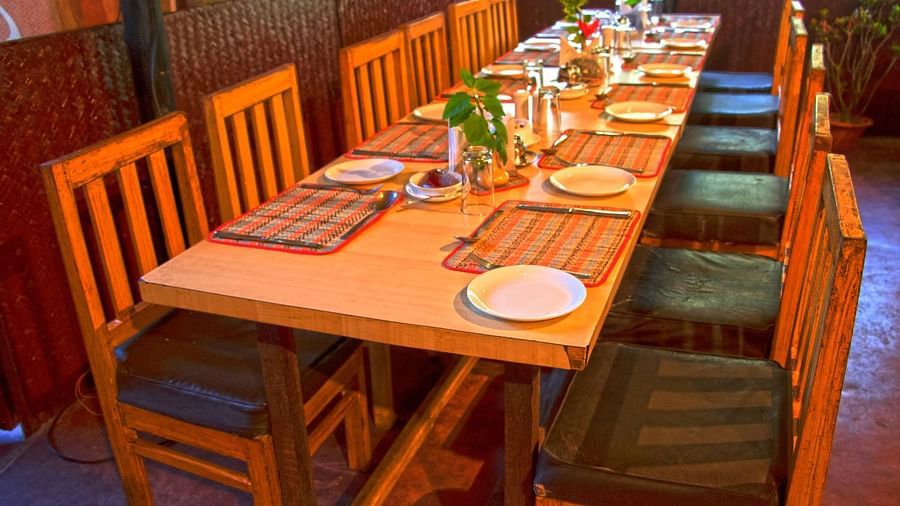  A dining setup at Lotus Eco Beach Resort Konark, with a long wooden table and comfortable chairs, ready for guests to enjoy a communal meal in a cosy environment.