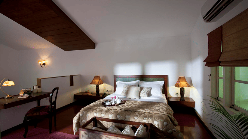 Elegant bedroom at Amanvana Resort and Spa featuring a double bed with padded headboard, warm lighting, wooden accents, and cosy decor .