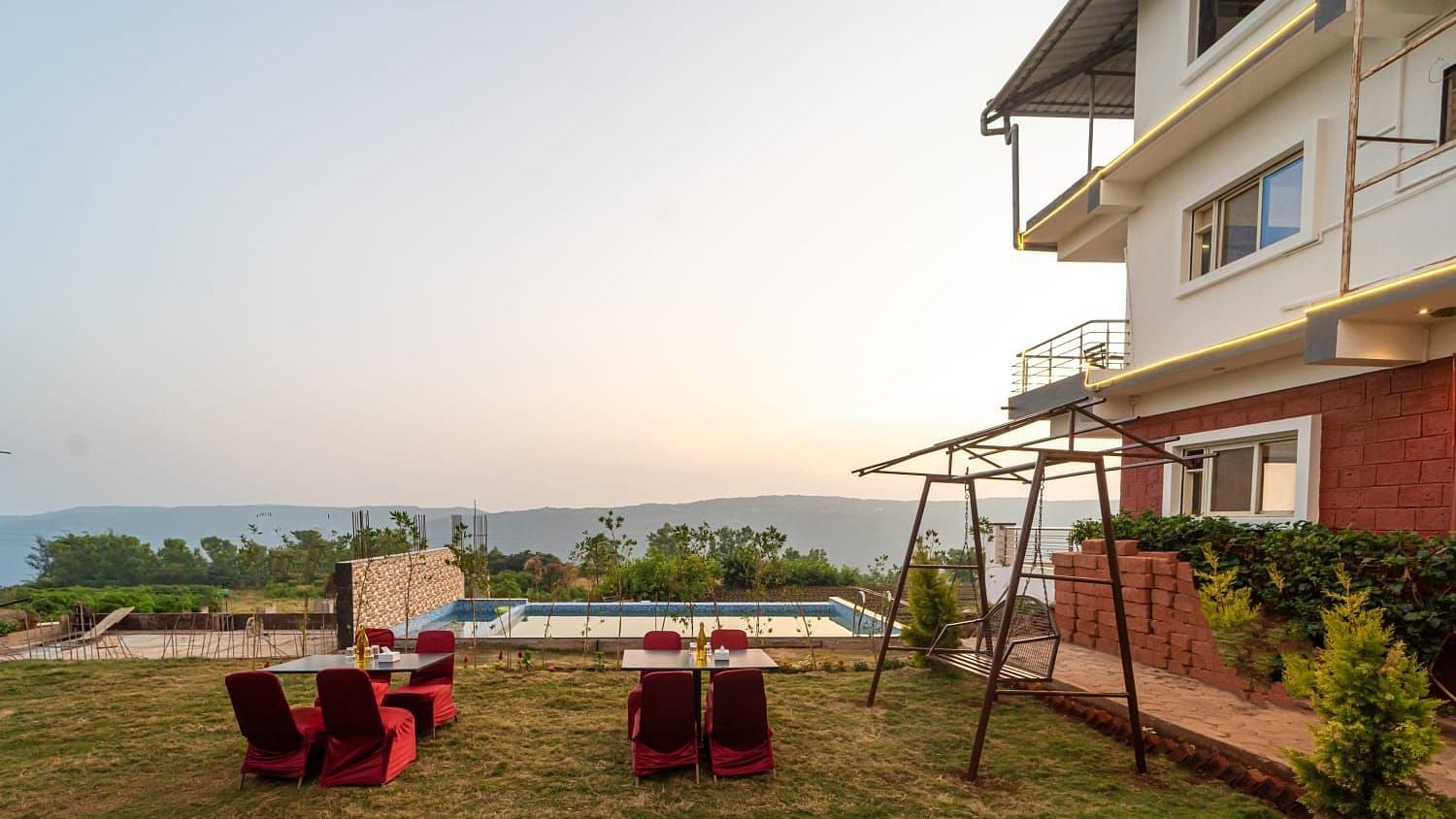 Outdoor lawn area next to a swimming pool featuring seating arrangements and a swing.