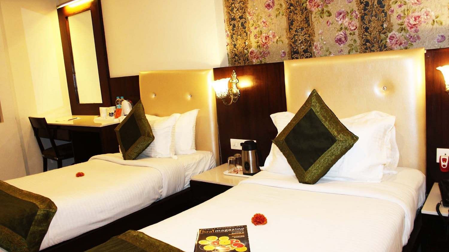 A cosy hotel room with two single beds, beige headboards and a work desk - TGI Apple Inn, Jaipur 