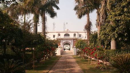 A facade image of  MudFort Kuchesar with a tiled pathway leading to the hotel