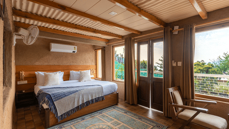 Sun-drenched bedroom with large windows offering panoramic views of the hills at Maati Resort By The Lake Hill, Jeolikote.