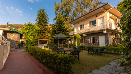 Beautifully manicured garden lawn and cottage-style buildings at Maati Resort By The Lake Hill, Jeolikote.