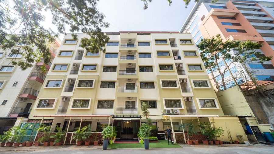 A modern multi storey building with numerous windows stands against a clear sky, showcasing the exterior of Lords Midtown Suites.