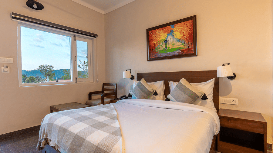 Modern bedroom featuring colourful wall art and large windows overlooking the valley at Maati Resort By The Lake Hill, Jeolikote.