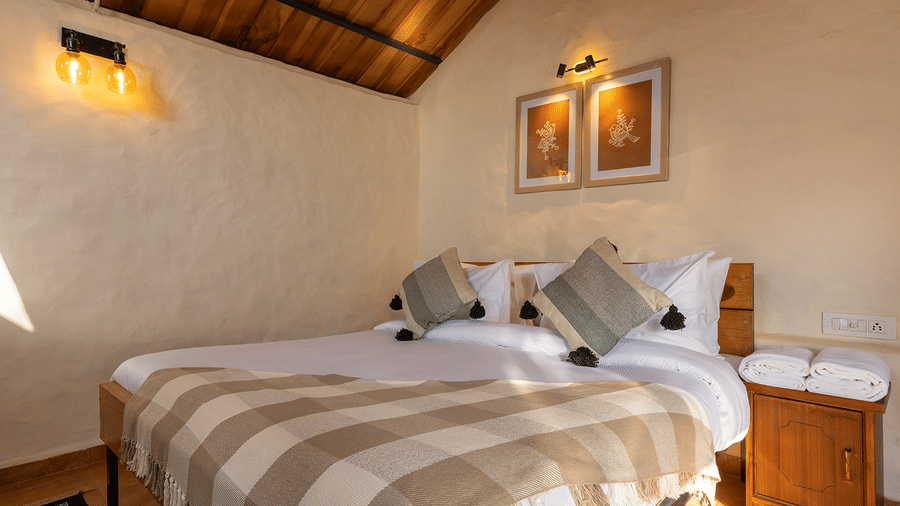 Cottage bedroom with a gabled wooden ceiling and warm bedside lighting at Maati Resort By The Lake Hill, Jeolikote.