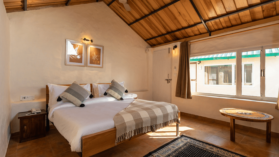 Sunlit guest room featuring a large window and a wooden vaulted ceiling at Maati Resort By The Lake Hill, Jeolikote.