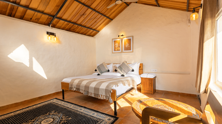 Bright cottage bedroom with natural sunlight, wooden ceilings, and traditional rugs at Maati Resort By The Lake Hill, Jeolikote.