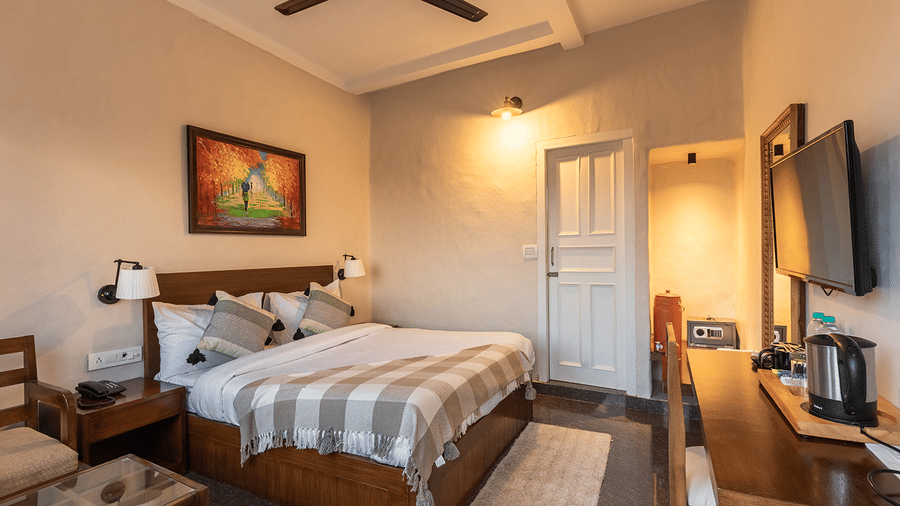 Minimalist double room with a work desk, television, and warm interior lighting at Maati Resort By The Lake Hill, Jeolikote.