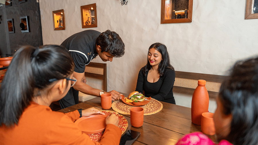 Friends enjoying a meal together in a cosy, warm-lit dining area at Maati Resort By The Lake Hill, Jeolikote.