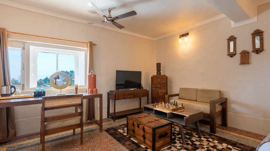 Elegant living space inside a luxury suite with a study desk, sofa, and trunk-style coffee table at Maati Resort By The Lake Hill, Jeolikote.