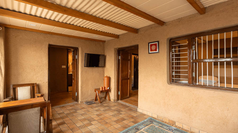 Spacious suite interior with traditional mud-finish walls and wooden beamed ceilings at Maati Resort By The Lake Hill, Jeolikote.
