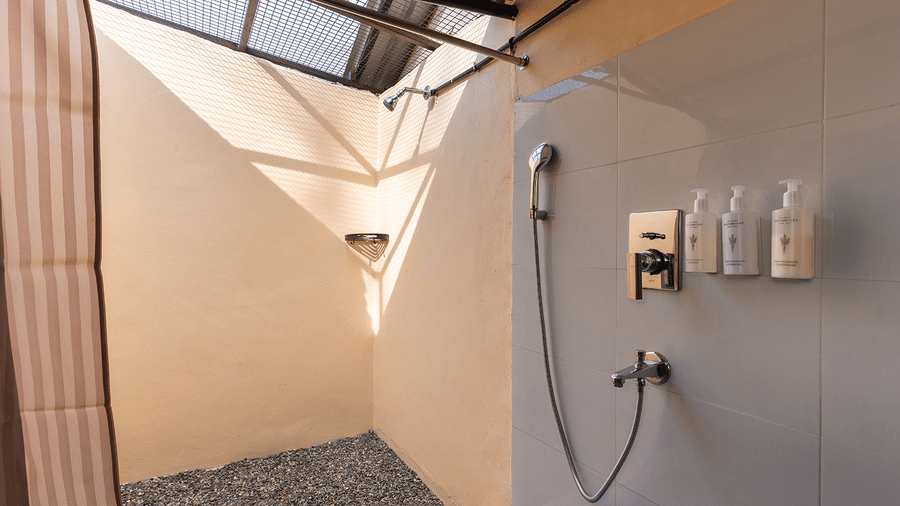 A unique open-air style shower area with modern chrome fixtures and stone flooring at Maati Resort By The Lake Hill, Jeolikote.