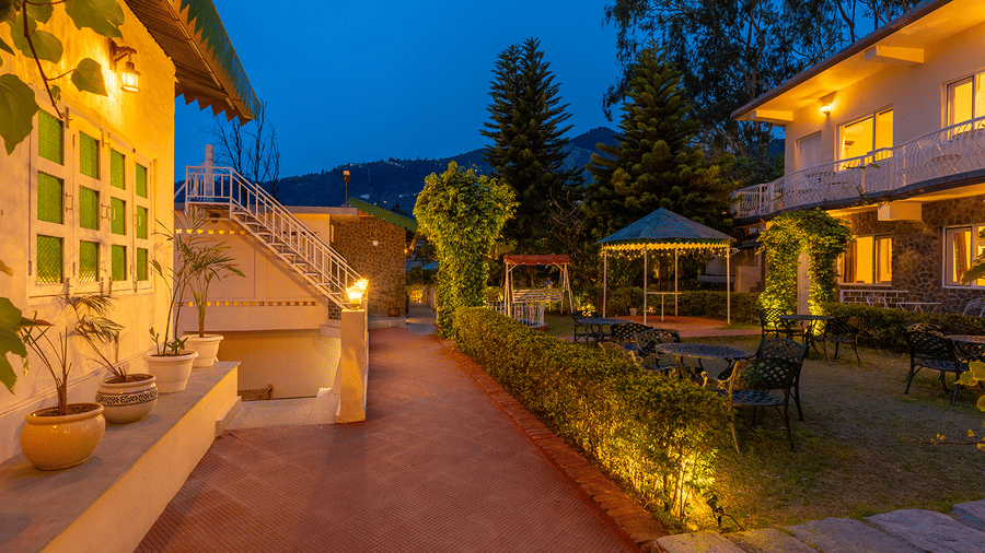 Beautifully lit resort walkway and garden area during twilight at Maati Resort By The Lake Hill, Jeolikote.