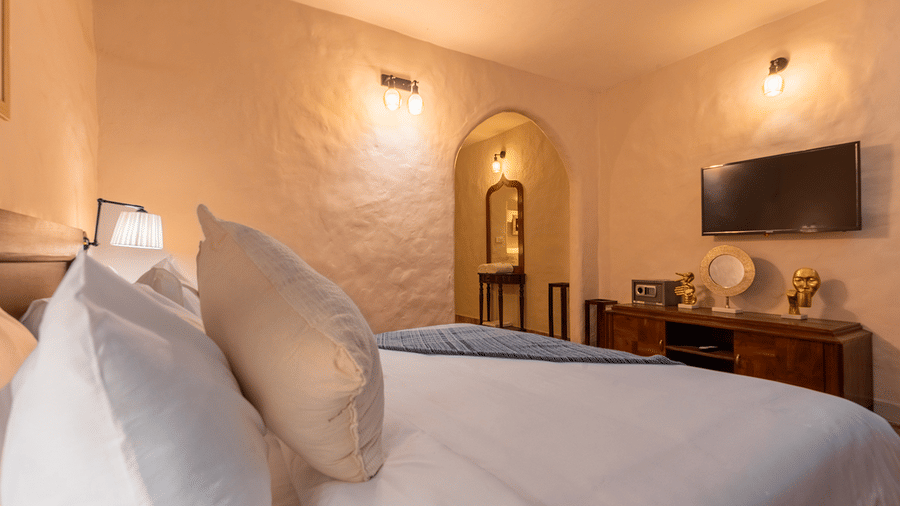 Cosy guest bedroom featuring textured white walls and a wall-mounted television at Maati Resort By The Lake Hill, Jeolikote.