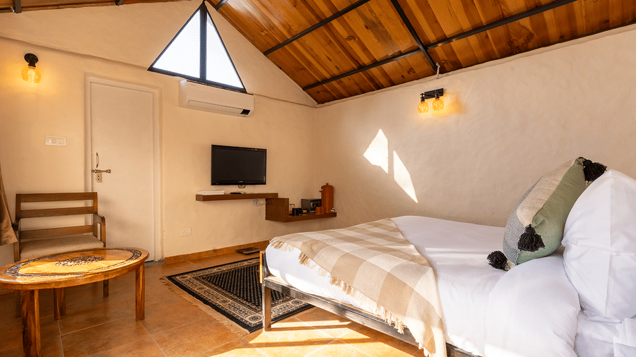 Open-concept room with a wall-mounted TV, seating area, and traditional wooden roof at Maati Resort By The Lake Hill, Jeolikote.