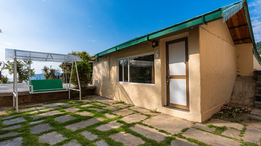 Exterior view of a cosy mountain cottage with a stone-paved courtyard at Maati Resort By The Lake Hill, Jeolikote.