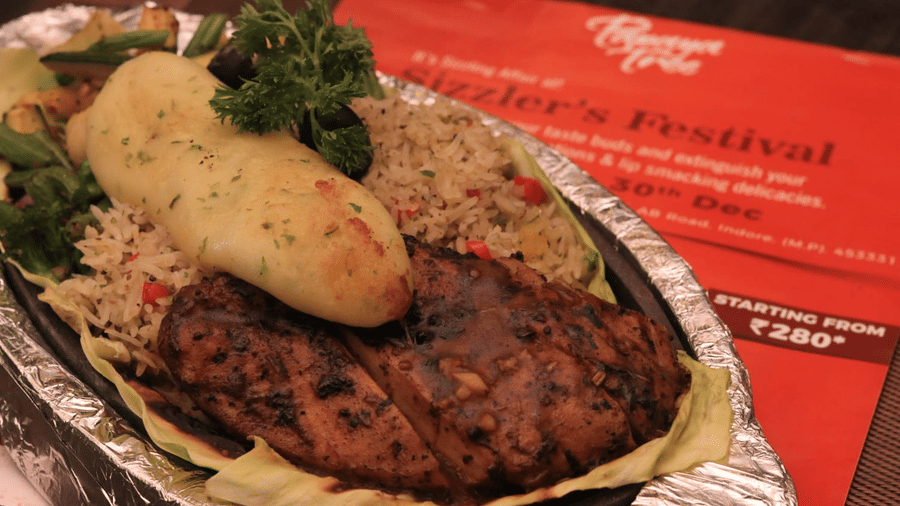 A sizzling platter featuring grilled chicken, aromatic rice, and bread served at Papaya Tree Hotels.