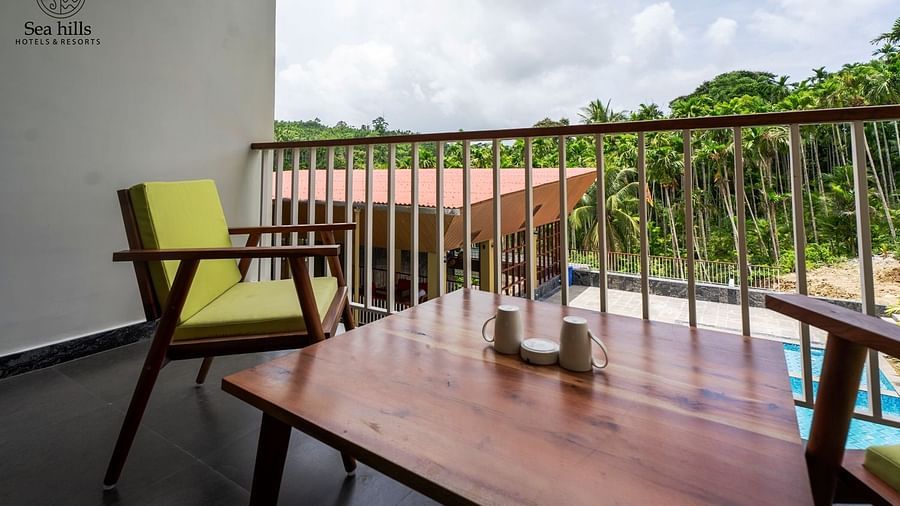 Another angle of the balcony with wooden seating and a view of the lush outdoors and pool - Sea Hills Resort, Swaraj Dweep (Havelock)