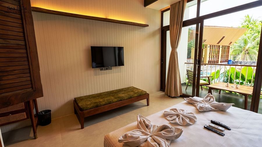 Bright, airy bedroom with large windows offering a scenic view and a modern TV mounted on the wall - Sea Hills Resort, Swaraj Dweep (Havelock)