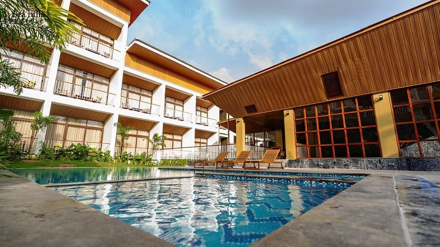 An exterior view of a modern hotel building with a swimming pool and sun loungers on a sunny day. - Sea Hills Resort, Swaraj Dweep (Havelock)