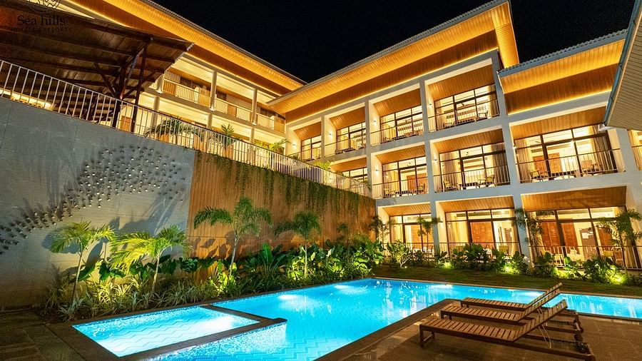 An exterior night view of a luxurious hotel building with a brightly lit swimming pool and lush landscaping. - Sea Hills Resort, Swaraj Dweep (Havelock)
