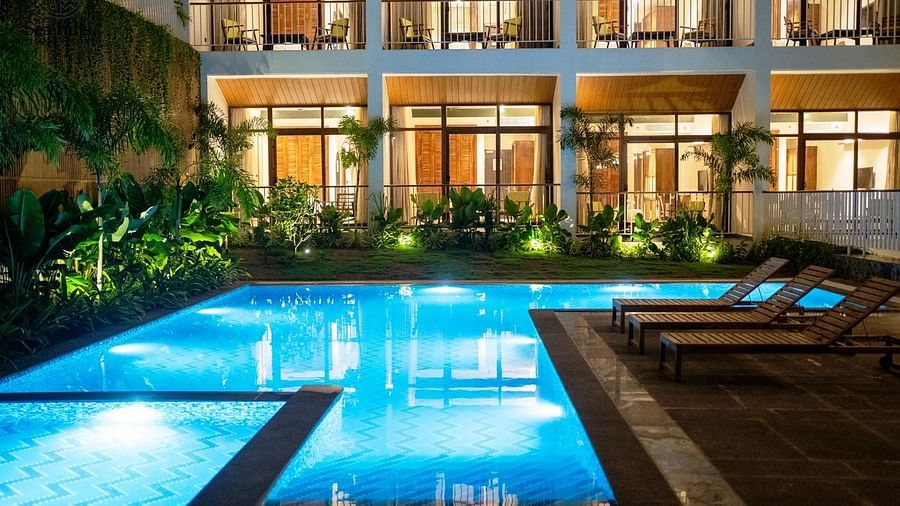 An exterior view of a hotel building with a brightly lit swimming pool in the foreground at dusk. - Sea Hills Resort, Swaraj Dweep (Havelock)