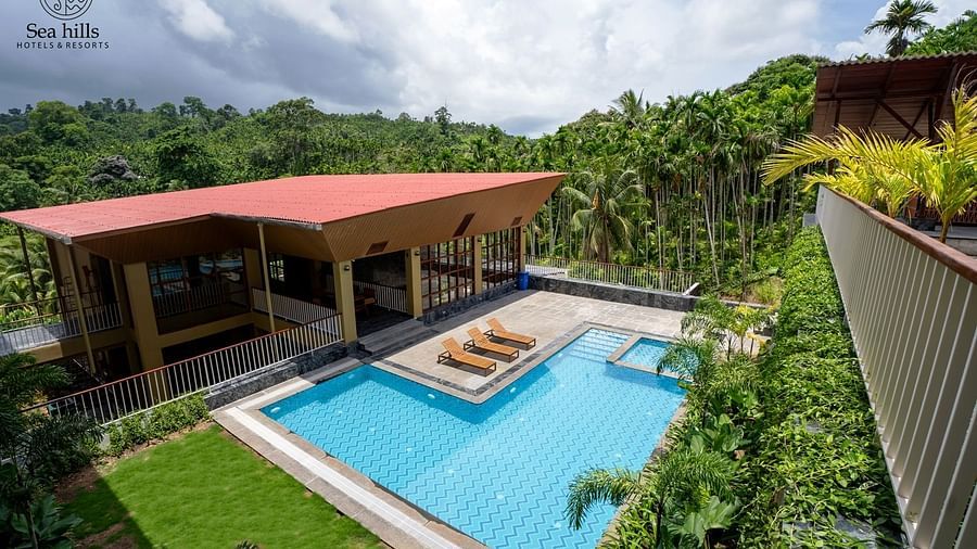 An elevated view of a hotel building with a red roof and a swimming pool, surrounded by lush trees. - Sea Hills Resort, Swaraj Dweep (Havelock)