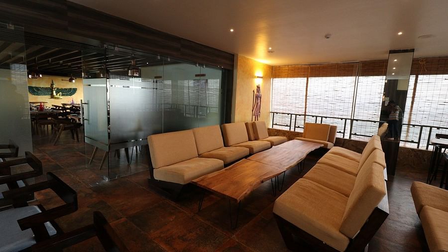 A sophisticated bar interior with dark wood shelving, bottles on display, and a framed piece of artwork featuring an animal's head - Sea Hills Hotels, Sri Vijaya Puram (Port Blair)