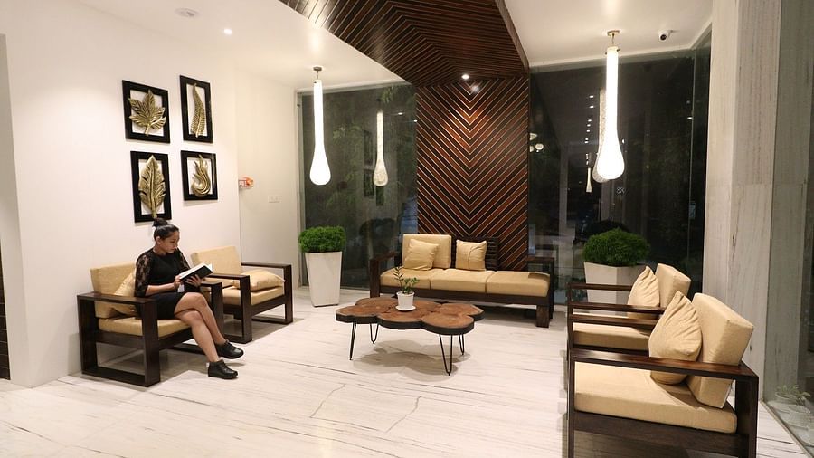 A well-lit hotel lounge area at night, showcasing comfortable sofas and armchairs arranged around a coffee table, with wall decorations - Sea Hills Hotels, Sri Vijaya Puram (Port Blair)