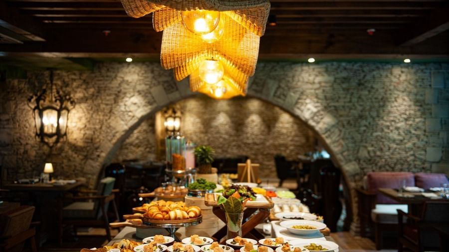 Close-up shot of the buffet table spread with well-plated dishes placed under the warm lighting from the unique chandelier at the Mila restaurant at The Evren, Vagator.