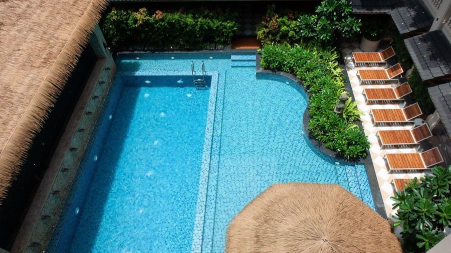 An empty swimming pool featuring calm waters lined with wooden sun loungers at The Evren, Vagator.