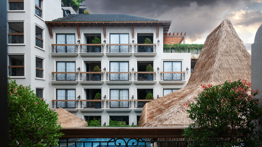 An exterior view of the multi-story hotel building at The Evren, Vagator, with a view of balconies and the swimming pool in the foreground.