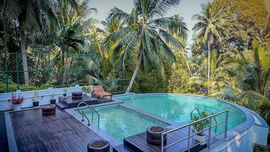 An outdoor swimming pool with clear blue water, surrounded by lush green tropical vegetation and trees - Sea Hills Hotels, Sri Vijayapuram (Port Blair)