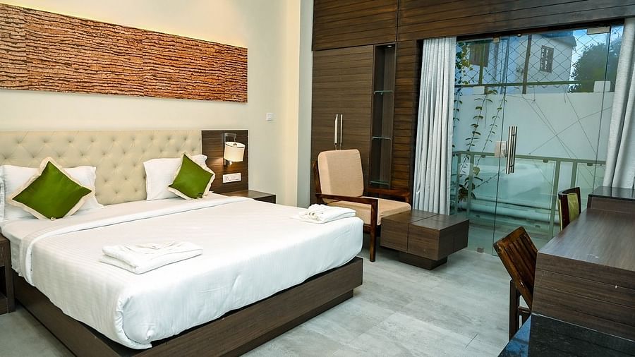 A bright hotel bathroom with a freestanding white bathtub, a toilet, a modern basin, and a large mirror, with light-coloured tiled walls - Sea Hills Hotels, Sri Vijaya Puram (Port Blair)