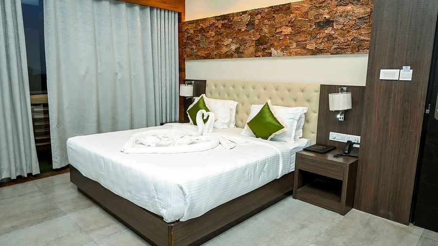 A bright hotel bedroom with a large bed, decorative swan-shaped towels, bedside tables, and modern wall decor - Sea Hills Hotels, Sri Vijaya Puram (Port Blair)