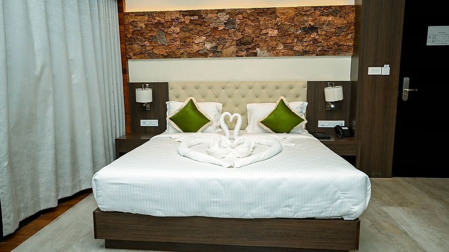 Another view of the bright hotel bedroom, showcasing the neatly made bed with swan towels, bedside lamps, and the contemporary design - Sea Hills Hotels, Sri Vijaya Puram (Port Blair)