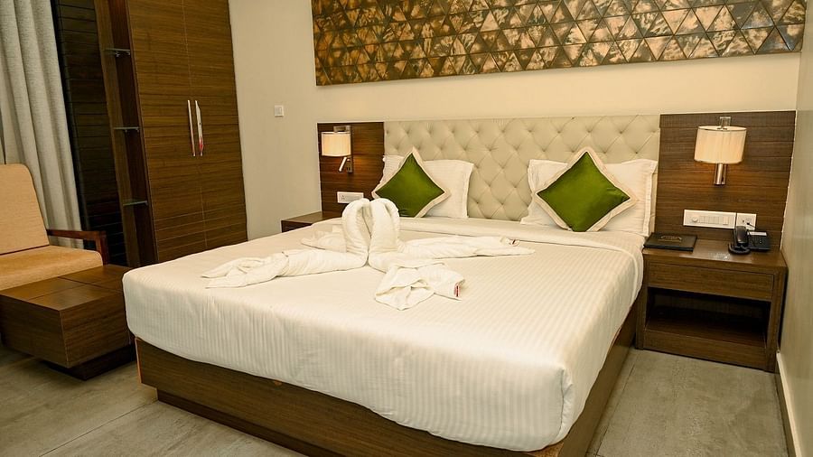 A hotel bedroom with a large white bed, bedside tables with lamps, and a decorative headboard, set in a modern room - Sea Hills Hotels, Sri Vijaya Puram (Port Blair)