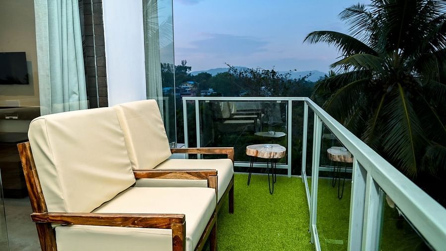 A small outdoor balcony with two light-coloured sofas and a low table, offering a view of lush greenery and the sky - Sea Hills Hotels, Sri Vijaya Puram (Port Blair)