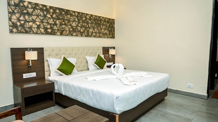 A small, cosy corner of a hotel room with a single armchair, a side table with a lamp, and a tall, dark curtain - Sea Hills Hotels, Sri Vijaya Puram (Port Blair)