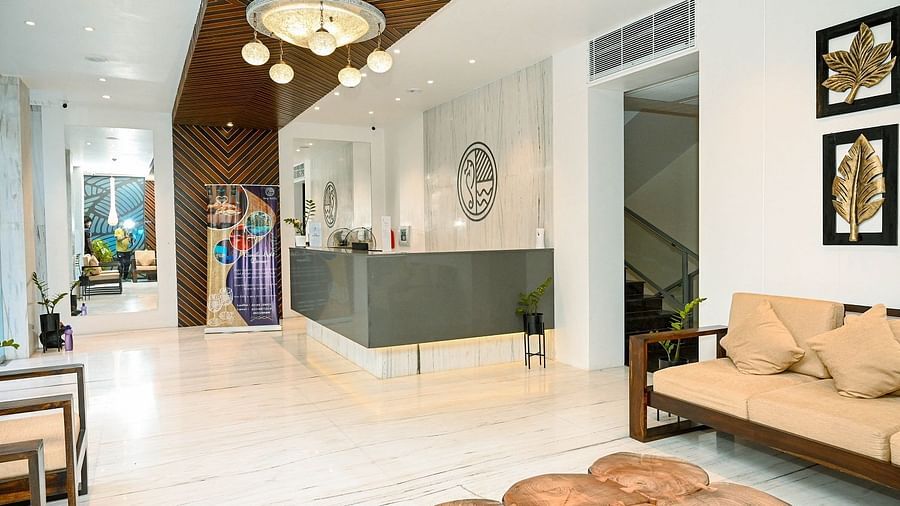Another angle of the hotel interior, showing a wider view of the corridor with seating and wall decorations, and a glimpse of the reception area - Sea Hills Hotels, Sri Vijaya Puram (Port Blair)
